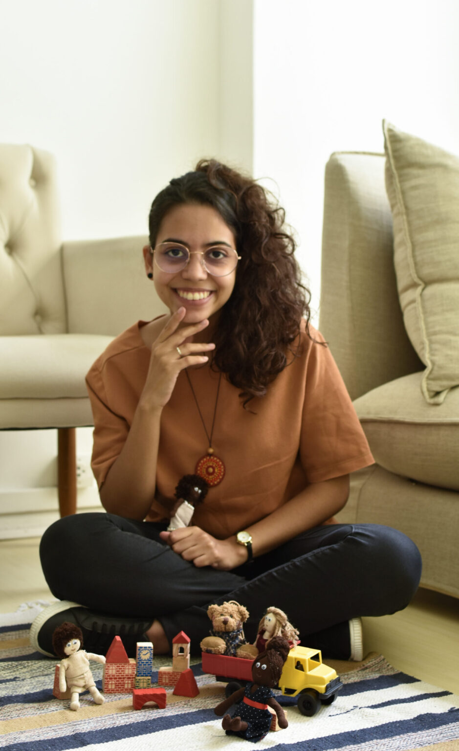Nathaly Araújo sentada no chão da clínica com brinquedos para o atendimento de crianças.